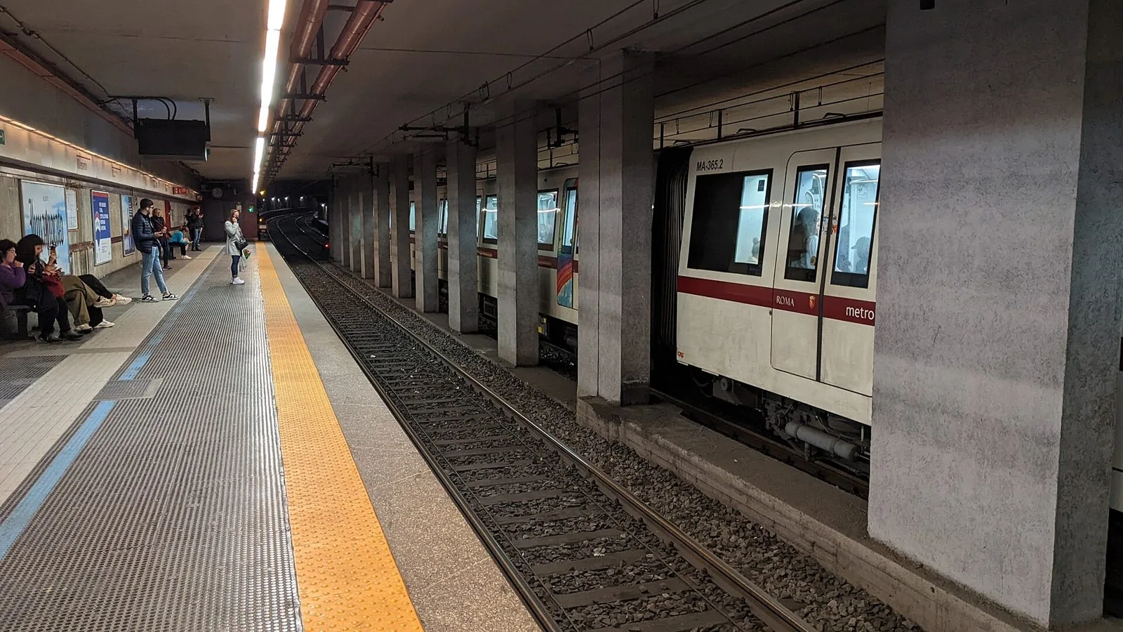 Banchina sotterranea della stazione Lepanto della metro A di Roma, con un treno bianco e rosso fermo al binario e alcuni passeggeri in attesa